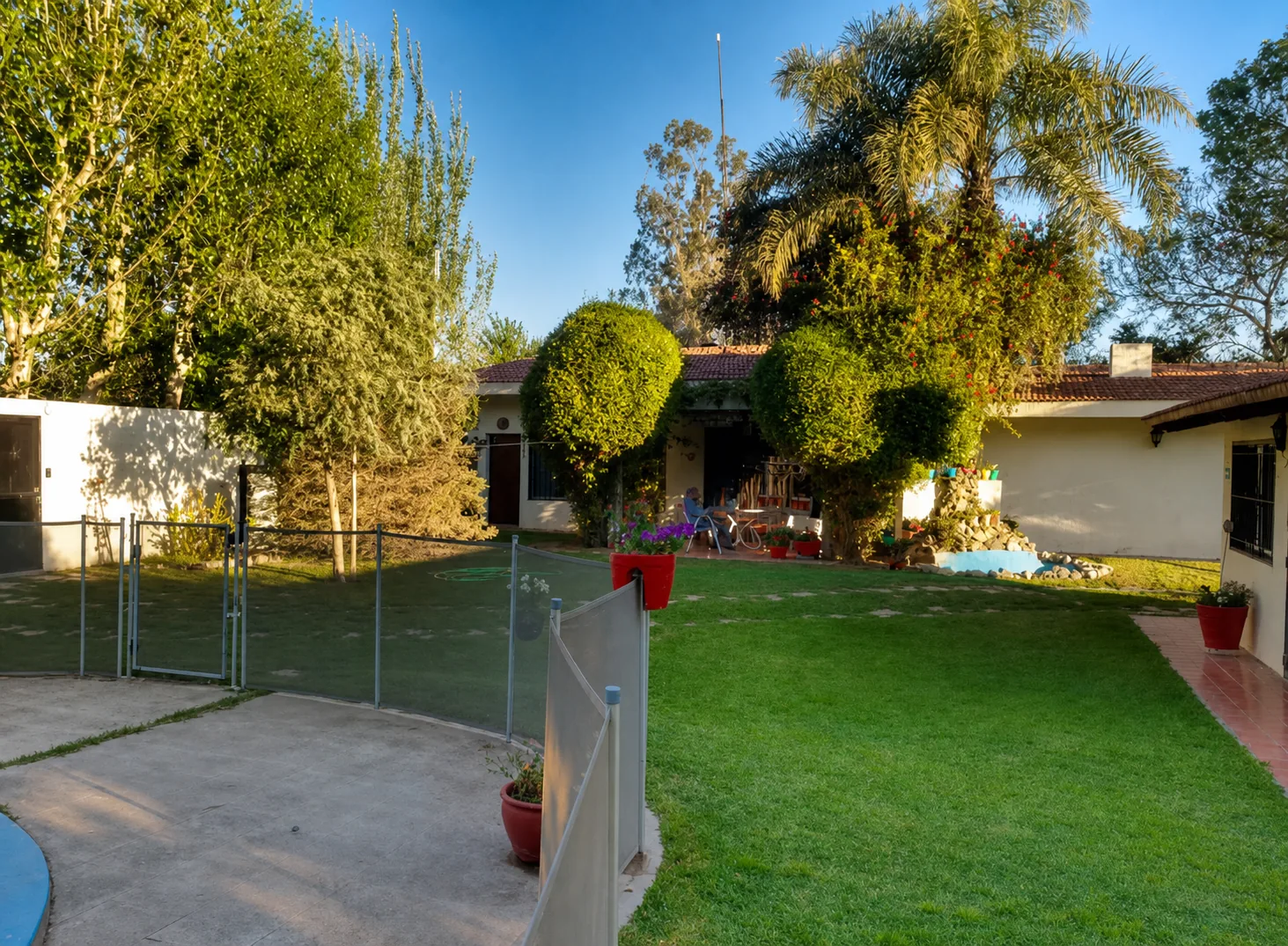 Jardín y sector cercado de la pileta de Complejo Los Aromos